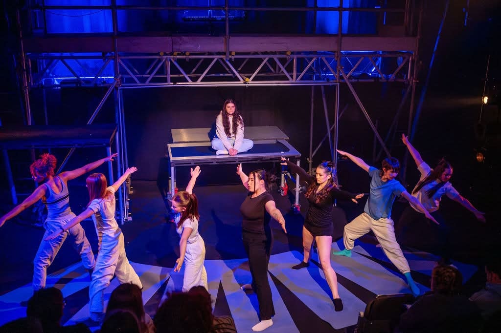 Singers and dancers performing under purple and magenta lighting